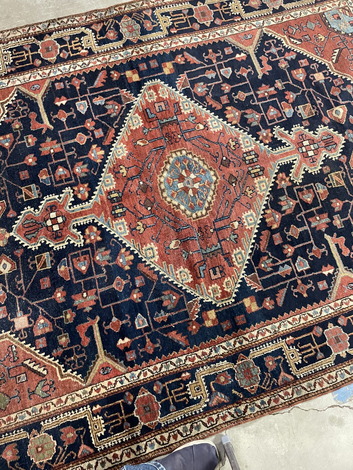 Coral and navy wool rug with serrated ivory edging and floral details
