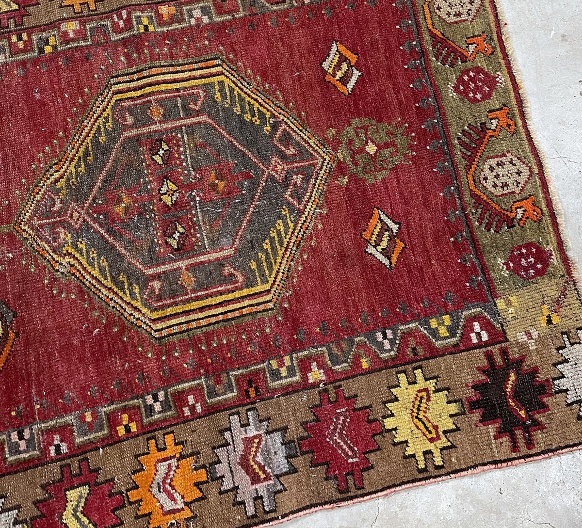 Detail of the worn red field, small diamonds and olive-green floral end panel.