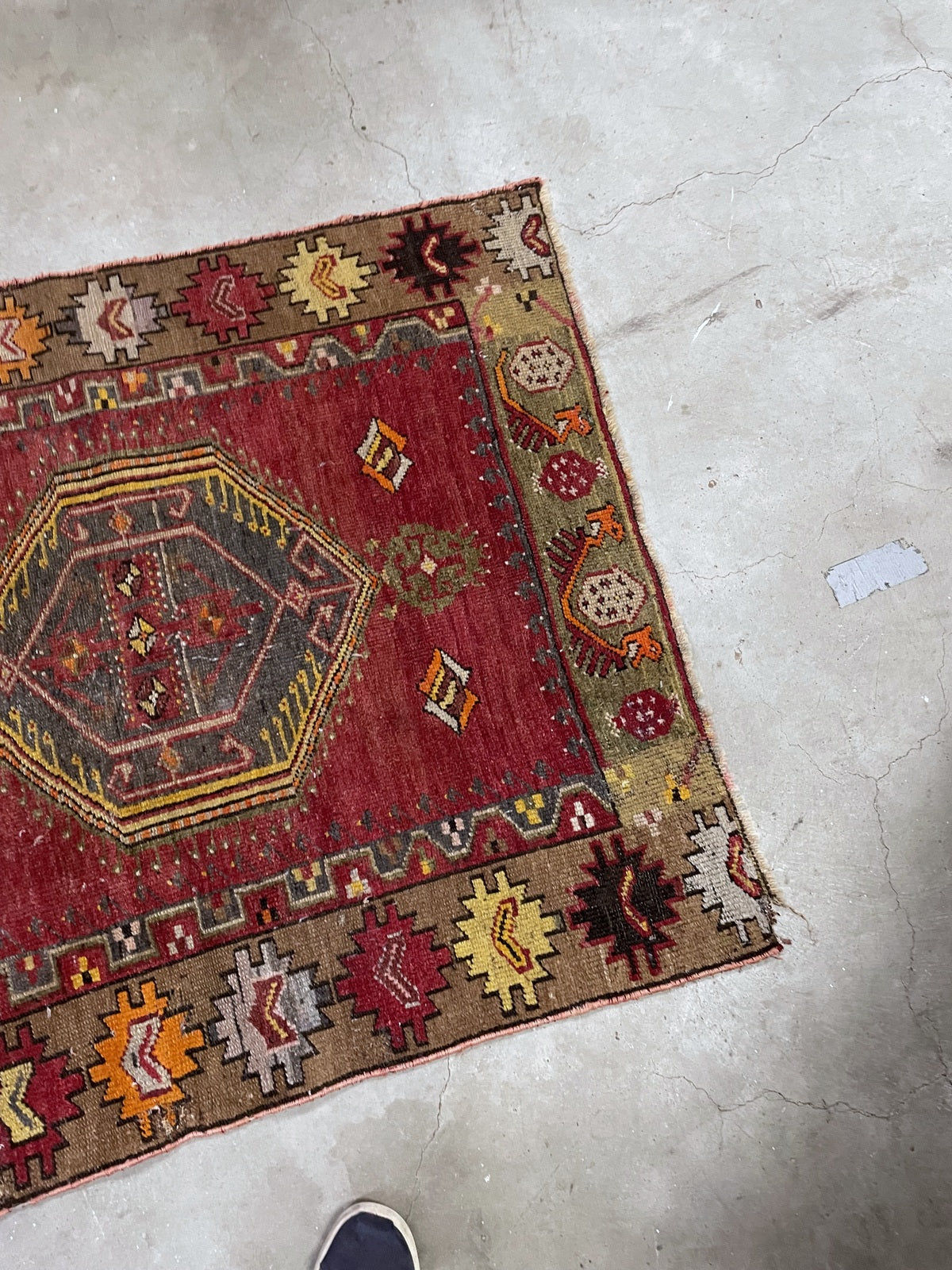 Angled view showing the medallion, geometric border and closely worn rug end.