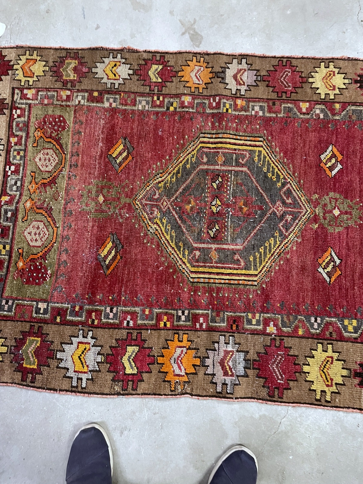 Angled rug detail showing low pile, dark medallion and multicoloured border motifs.