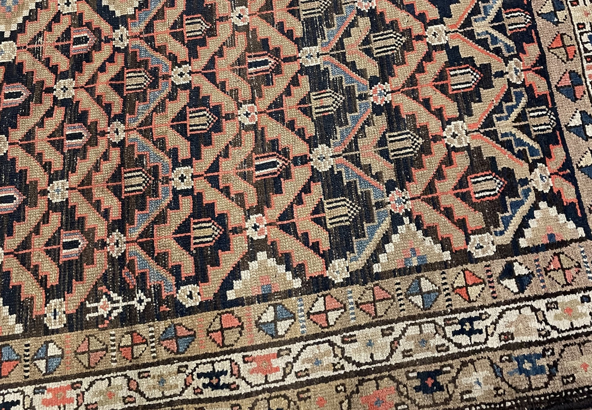 Angled rug end showing uneven fringe remnants and layered floral border bands.