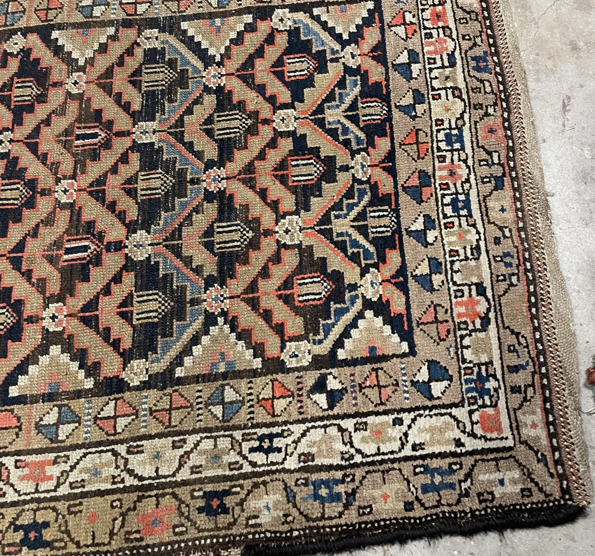 Worn navy field with visible knot structure beneath repeating floral motifs.