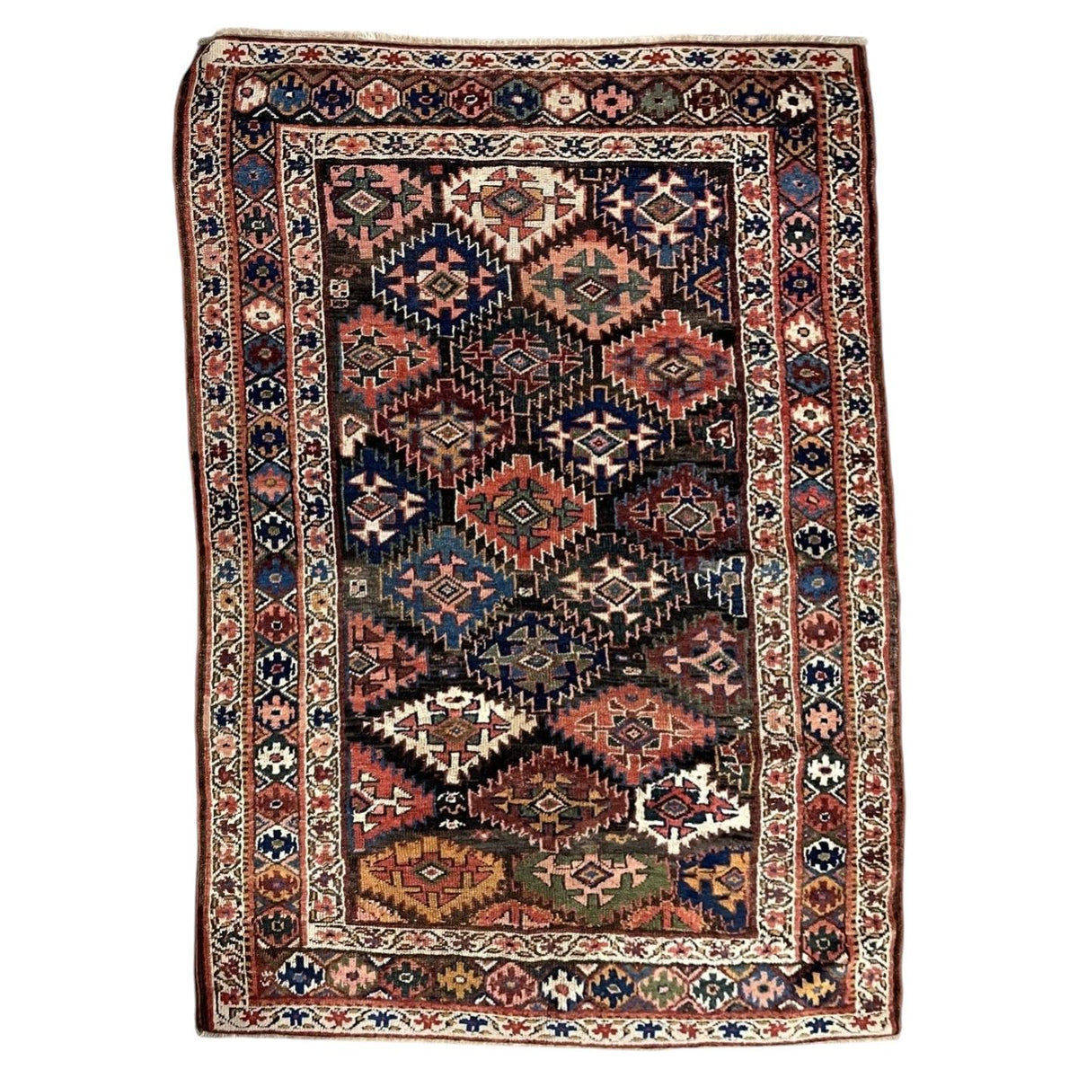 Full antique wool rug with multicoloured serrated medallions and ivory floral borders.