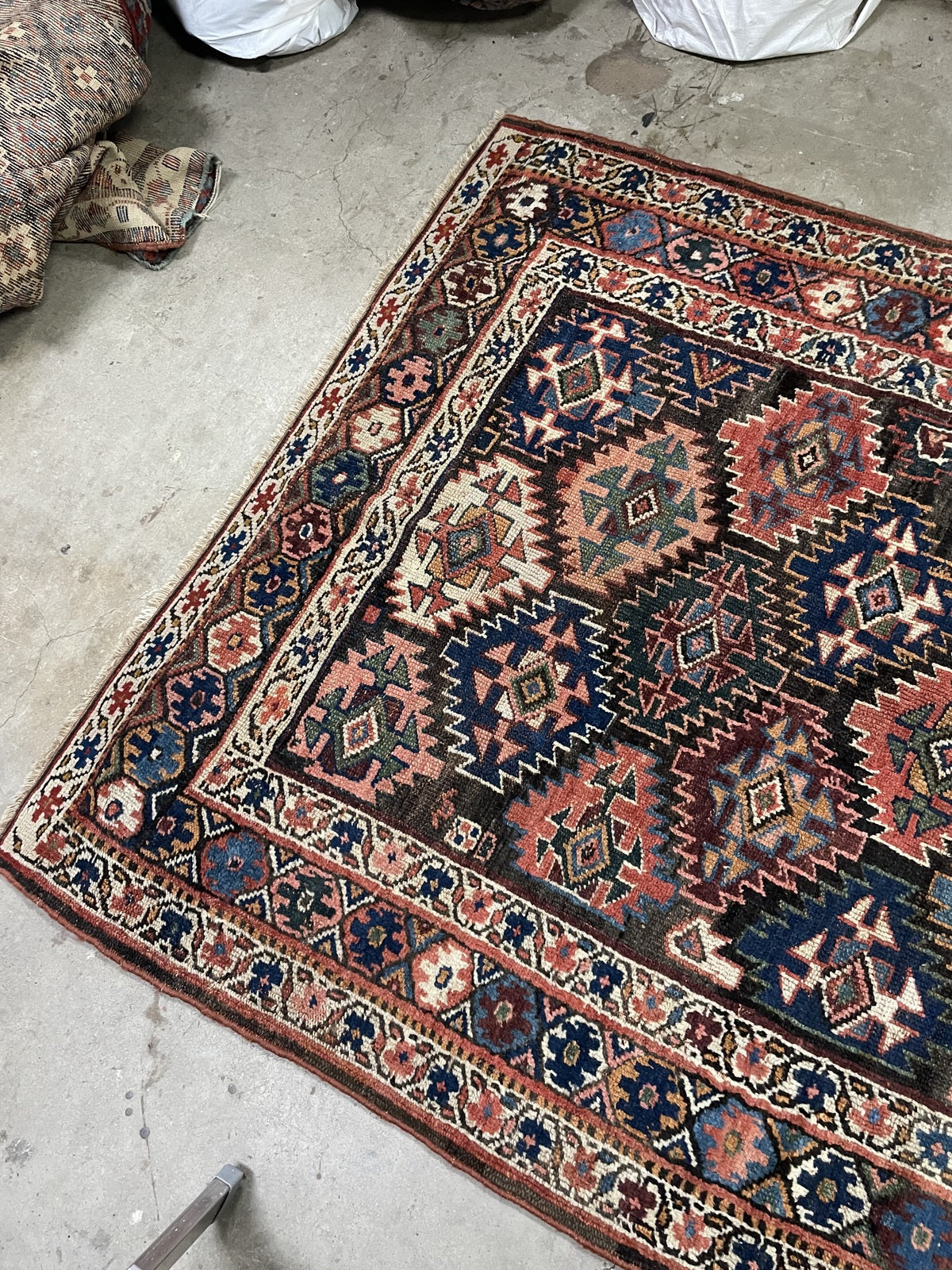Folded rug corner revealing the reverse weave beside the geometric patterned face.