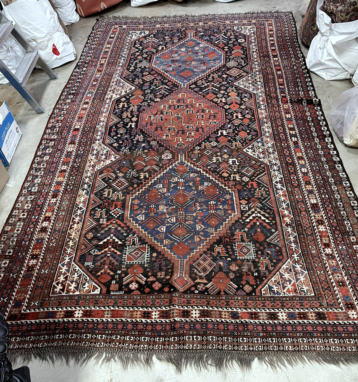 Rug end showing the blue medallion, corner panels, narrow patterned borders and fringe.
