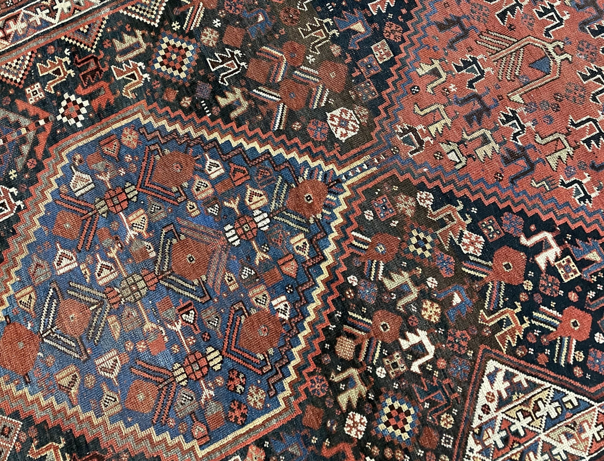 Corner view showing a blue medallion, animal figures, layered borders and uneven fringe.