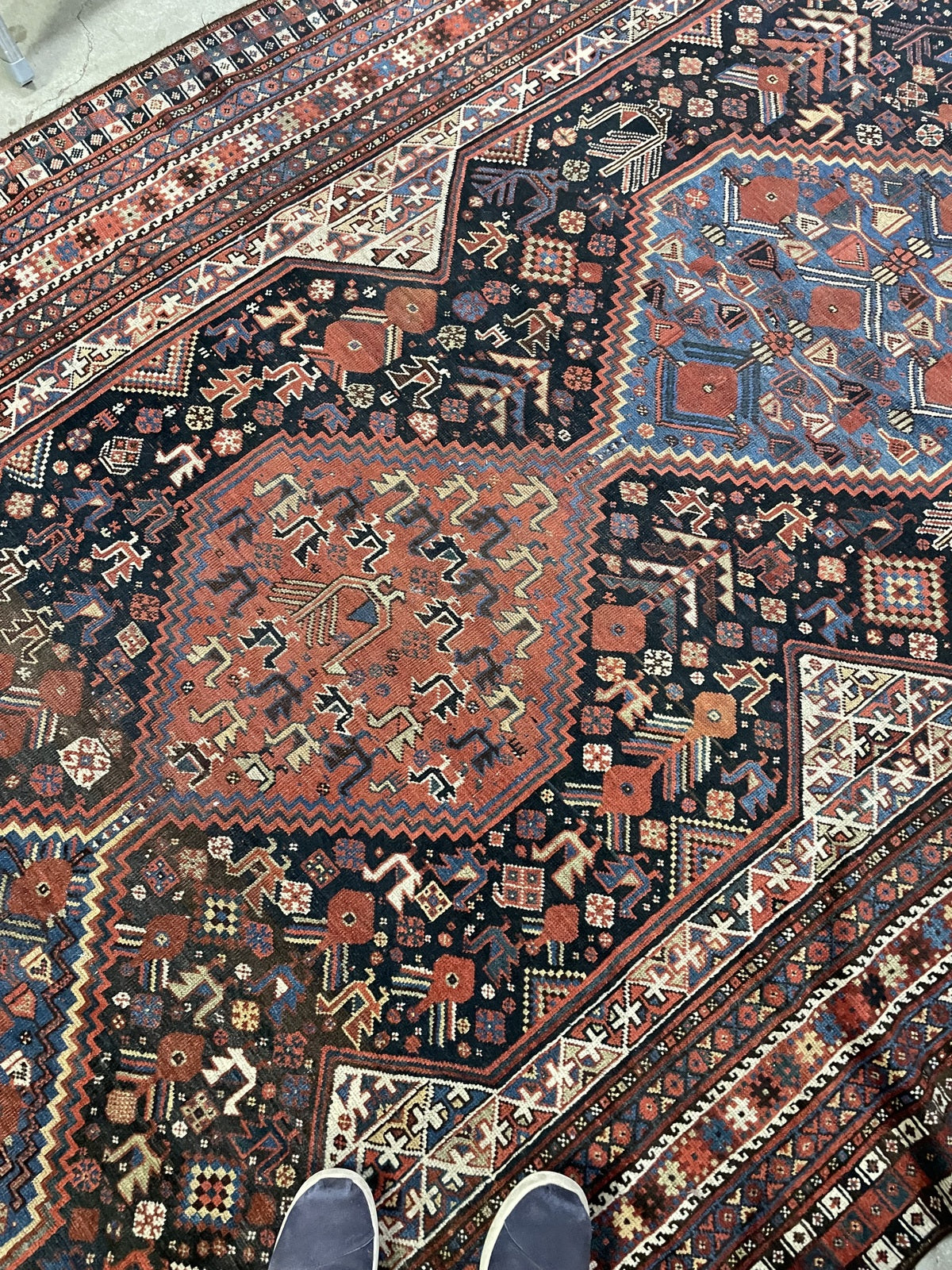Folded rug corner revealing the reverse weave beside the bird-patterned face.