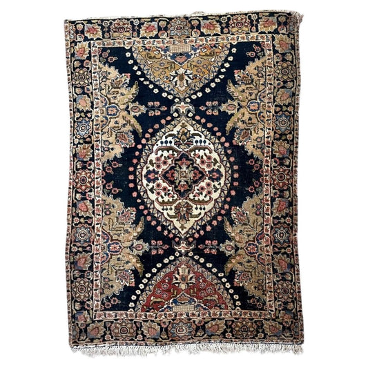Full antique wool rug with ivory central medallion, navy field and contrasting red and ochre end panels.