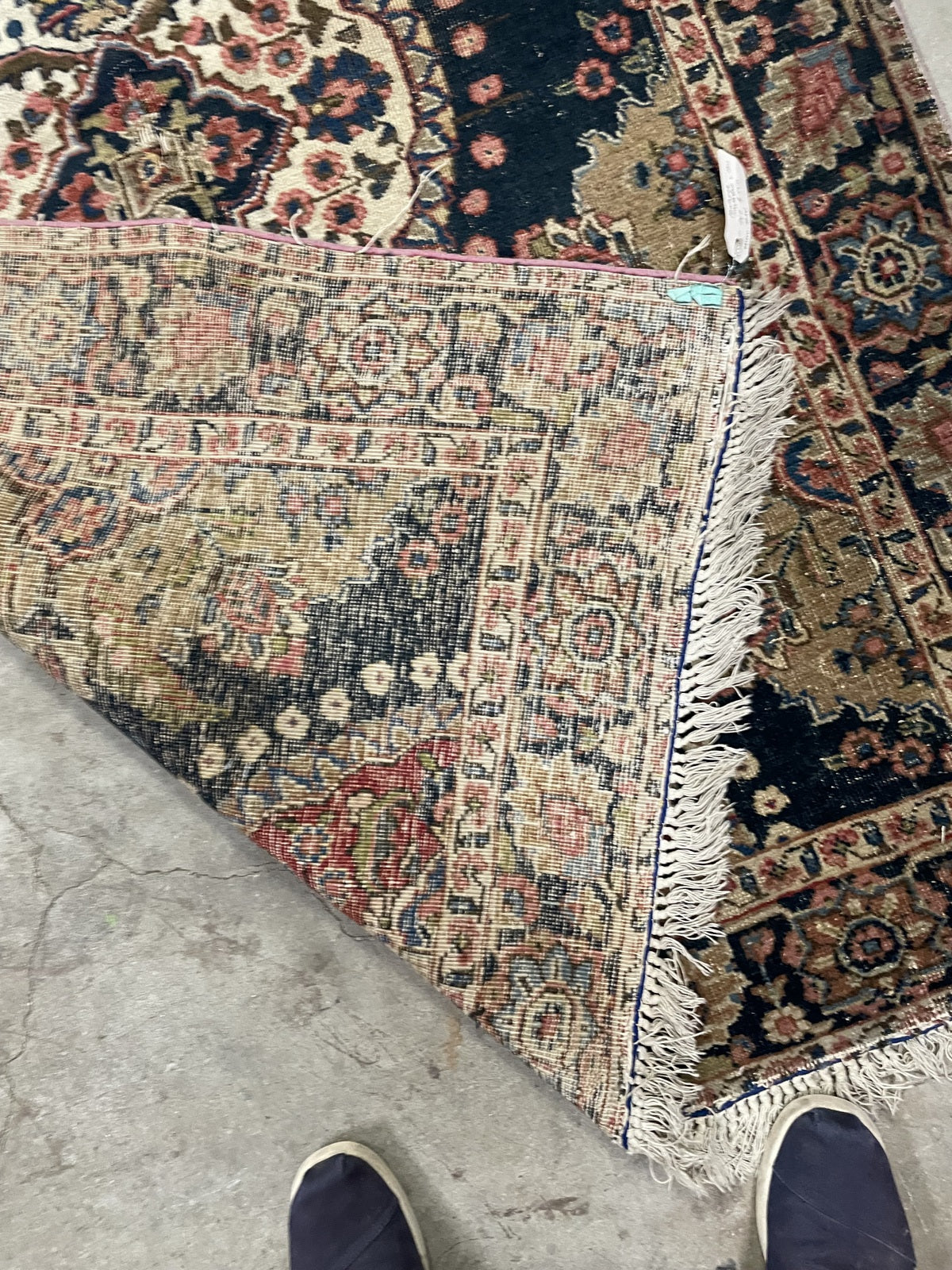 Worn navy field between the ivory medallion and red floral end panel.