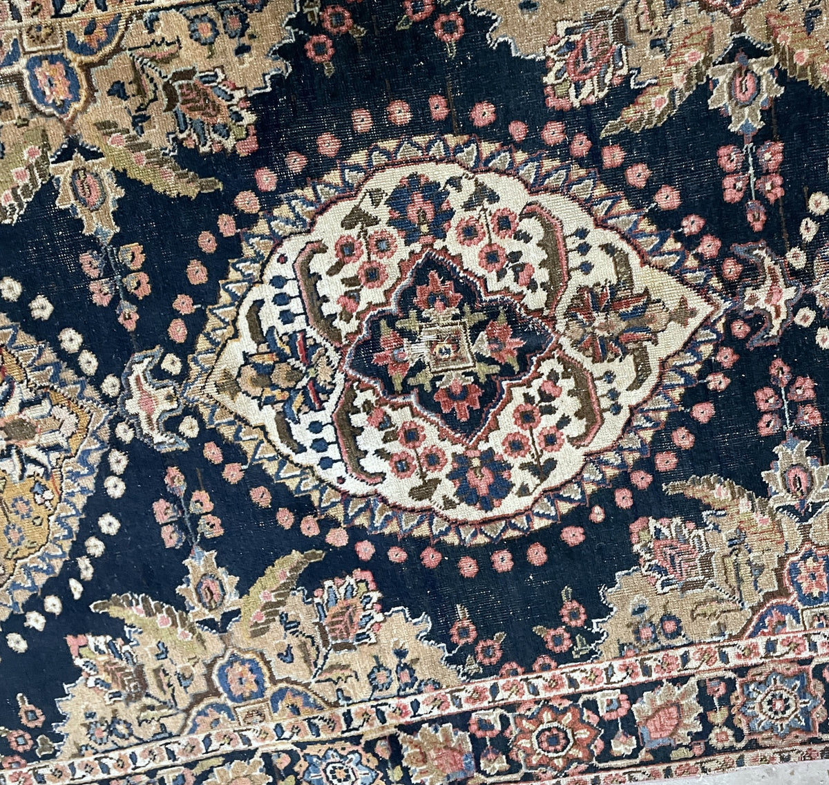 Folded rug corner revealing the reverse weave and fringe beside the patterned face.