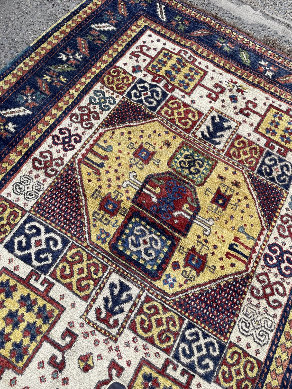 Folded rug corner revealing reverse weave and brown fringe beside the patterned face.