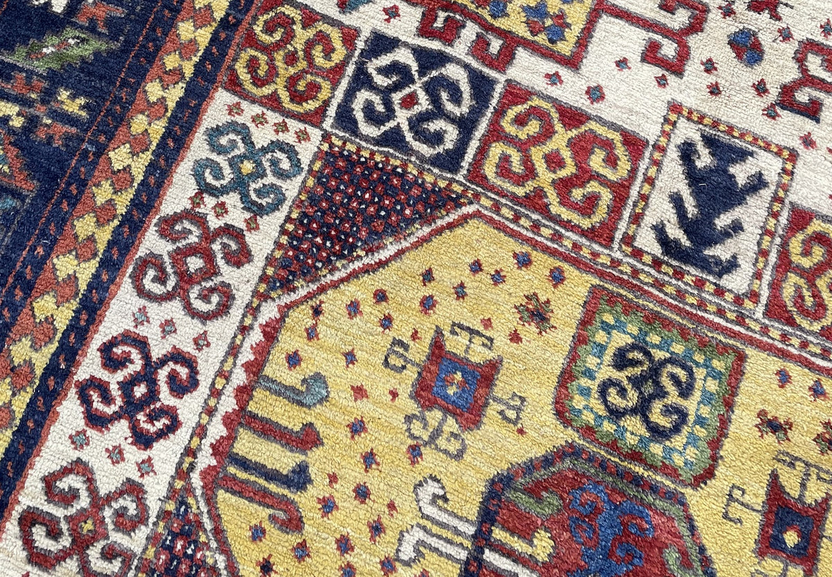 Broad navy border with red, green and ivory angular motifs between bright guard bands.