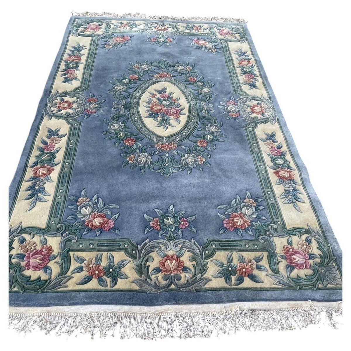 Chinese blue floral wool rug with an ivory oval medallion, sculpted flowers and fringed ends.