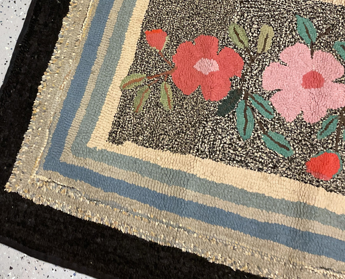 Rug end showing a blue flower, red bud, layered rectangular bands and rounded outer corner.