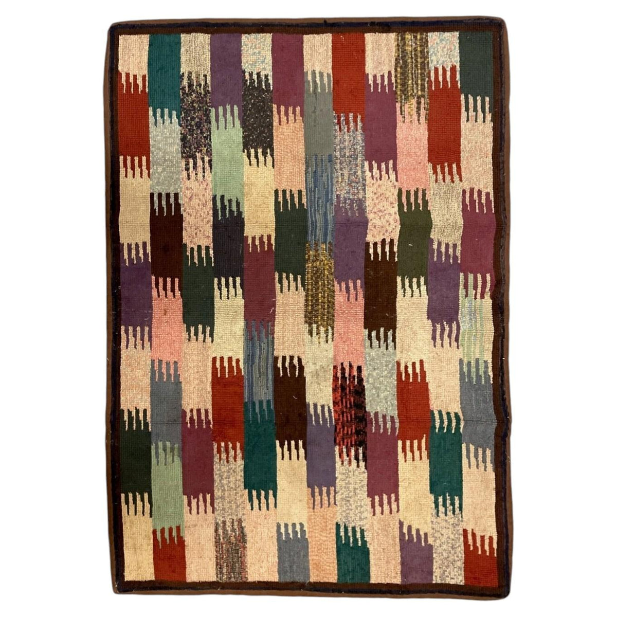 American hooked wool rug with interlocking multicoloured blocks, narrow dark border and brown binding.