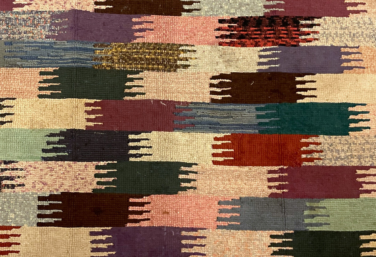 Attached handwritten sales tag beside a hooked rug corner with rust, cream and green blocks.