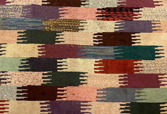 Attached handwritten sales tag beside a hooked rug corner with rust, cream and green blocks.