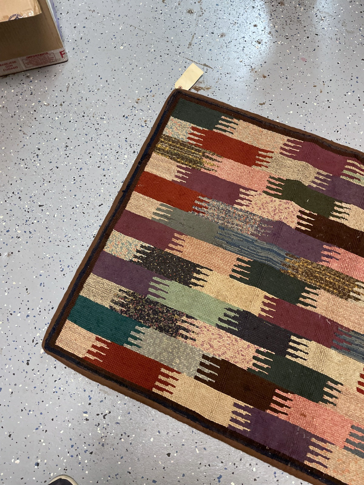 Close-up of plum, teal, rust and slate-blue geometric blocks in the hooked wool surface.