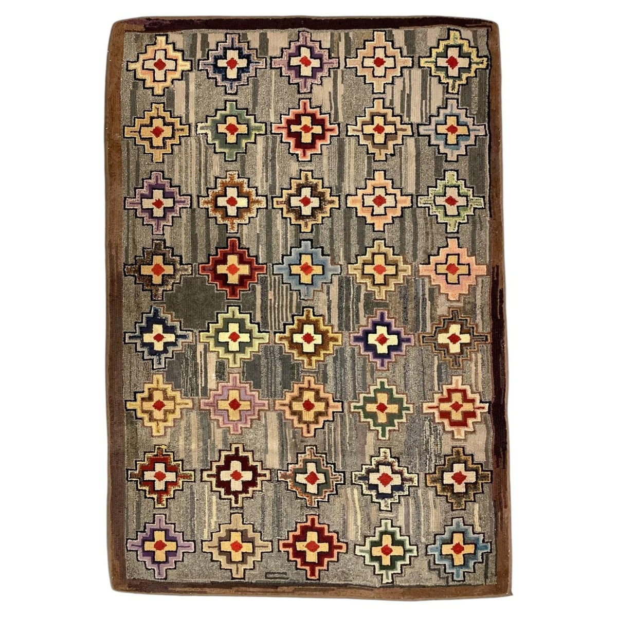 American hooked wool rug with colourful stepped-cross medallions, a striated grey field and brown border.