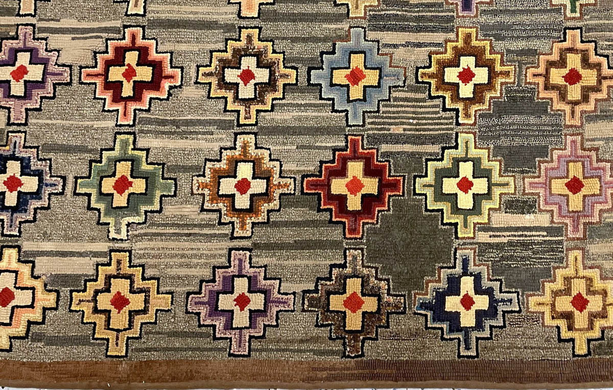 Repeated pale crosses with rust-red centres and blue, lilac, ochre and brown stepped outlines.