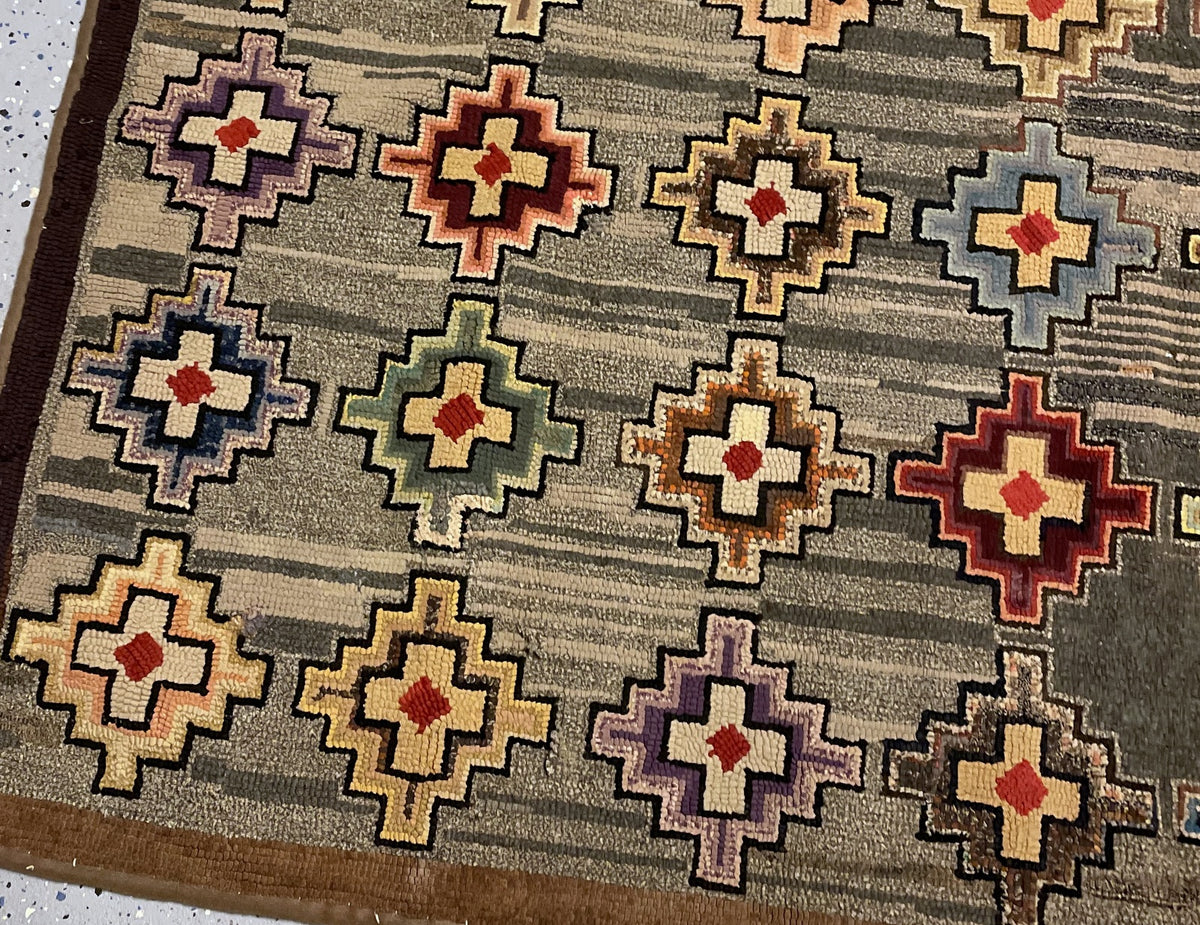 Close-up of stepped medallions against grey and cream streaks beside the worn brown border.