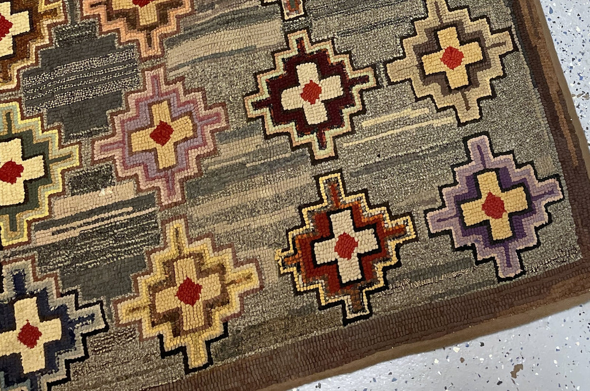 Horizontal view of the cross-pattern rug with striated ground and worn brown edges.
