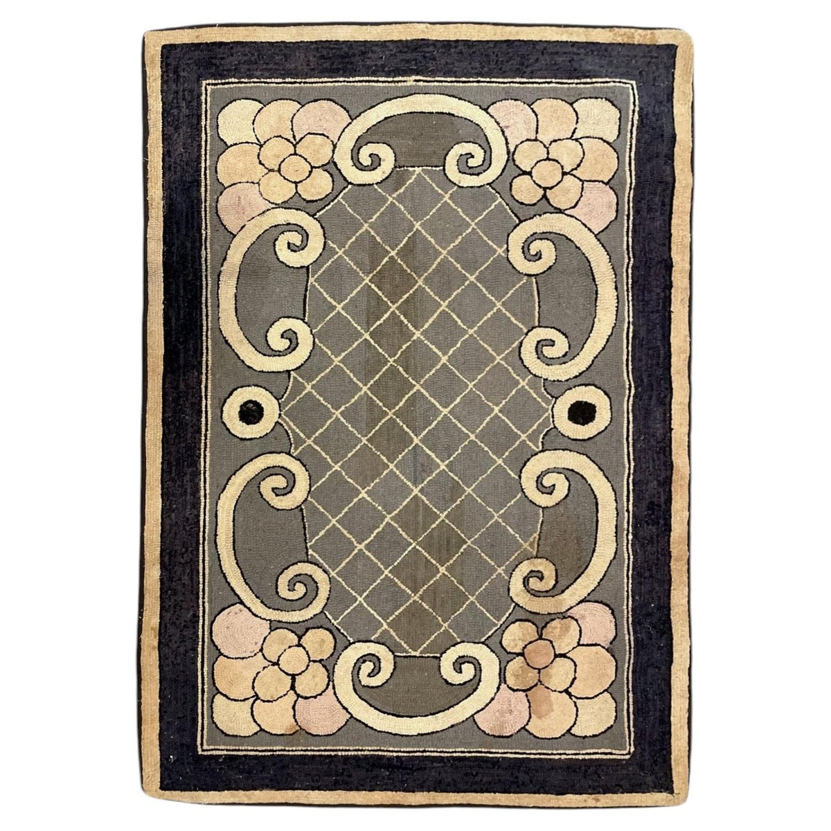 American hooked wool rug with pale corner flowers, cream scrolls, a diamond lattice and dark border.