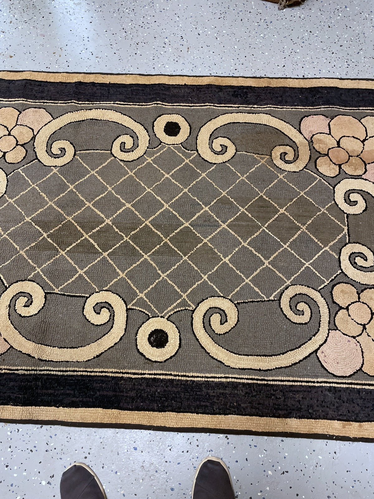 Cream diamond lattice on grey beside paired scrolls and a circular dark-centred accent.