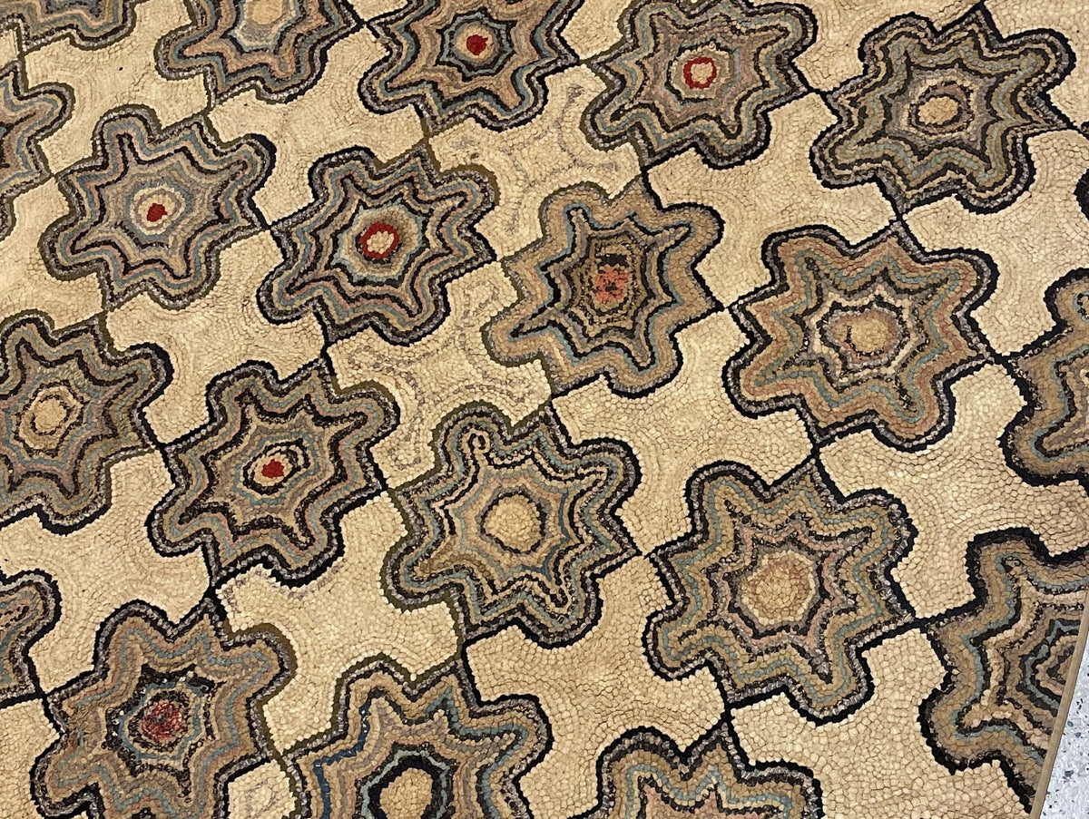 Full-length cotton rug with repeating geometric rosettes and a borderless cream field.