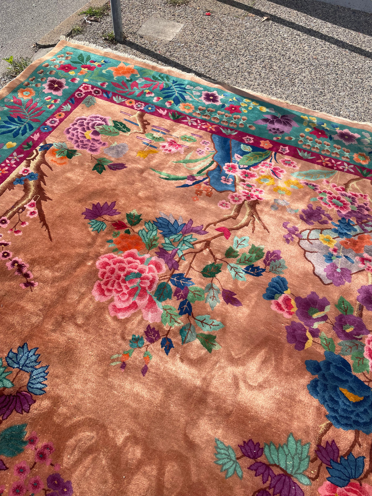 Peach wool rug with scattered floral sprays, decorative vases and a broad green border.