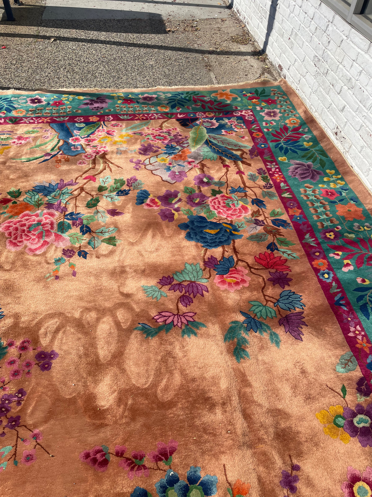 Chinese floral rug showing pink and purple blossoms, blue flowers and worn pale fringes.