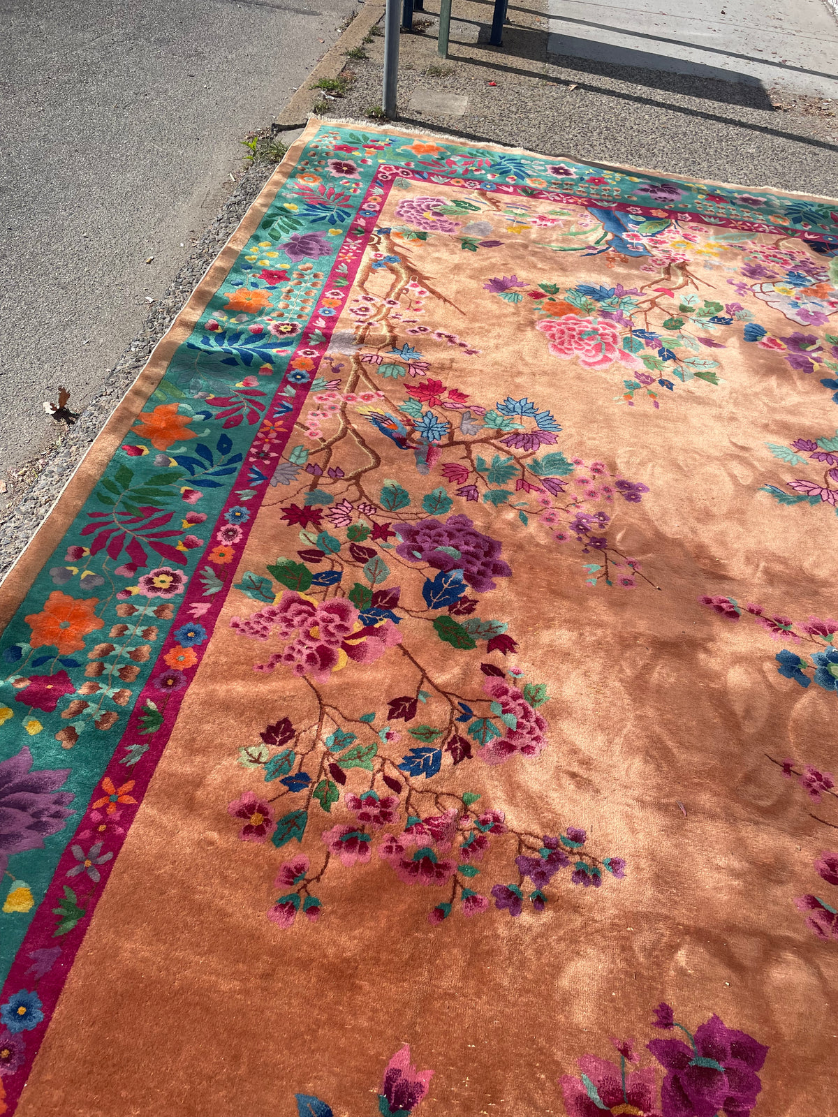 Detail of flowering branches and blue decorative vase motifs against the peach wool field.