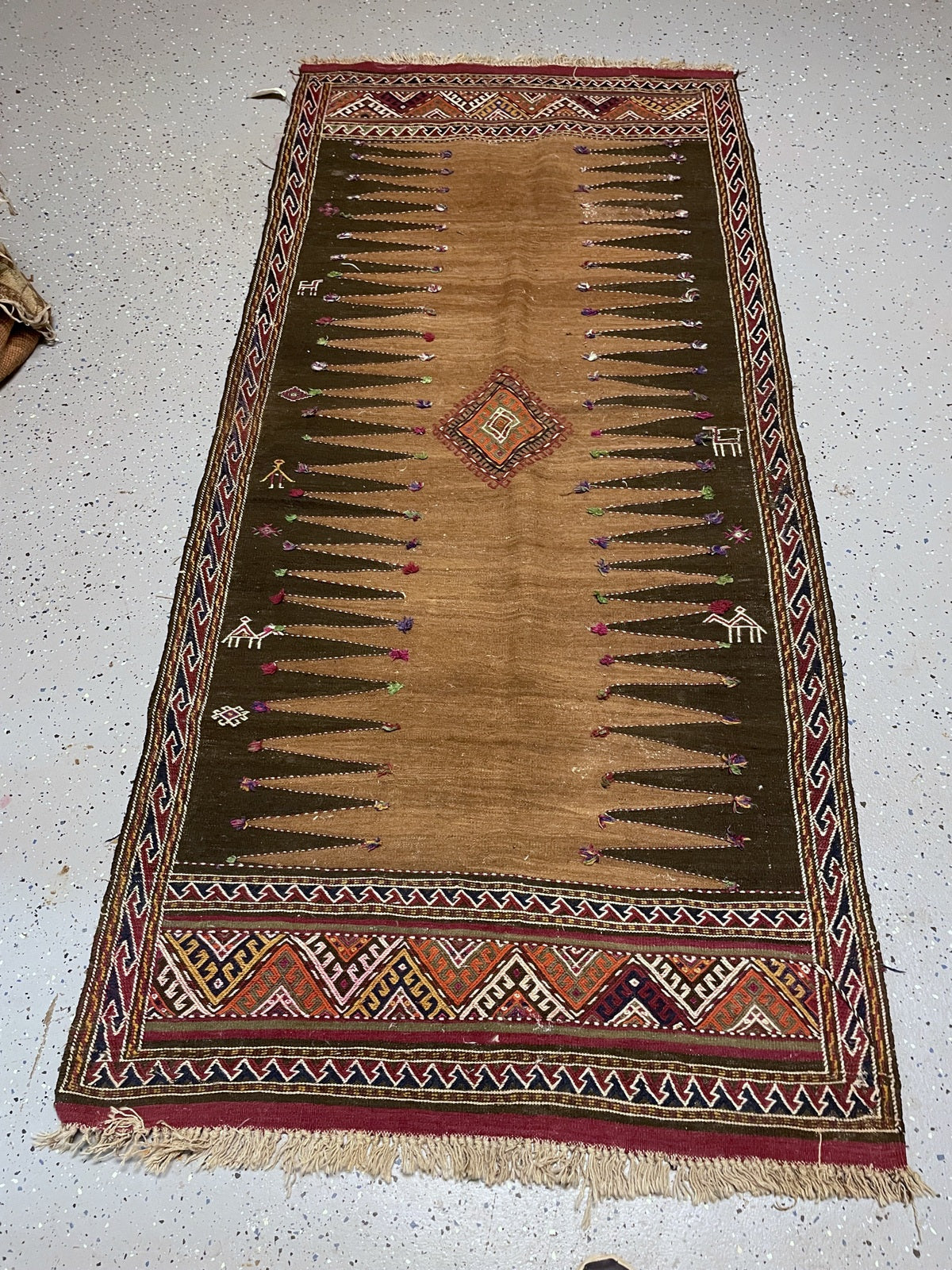Close-up of an ivory animal and geometric ornament beside multicoloured tufts and stitched serrated outlines.