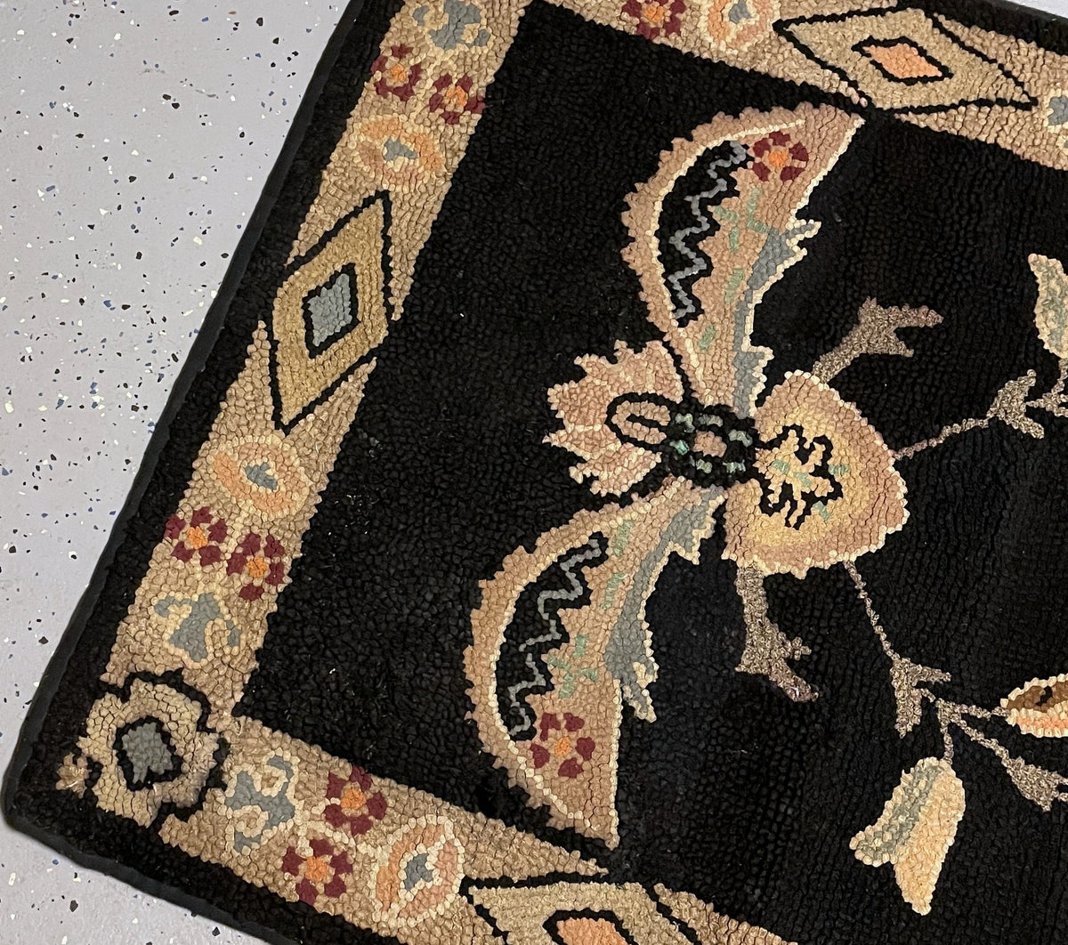 Lifted corner revealing the woven backing, black bound edge and attached handwritten tag.