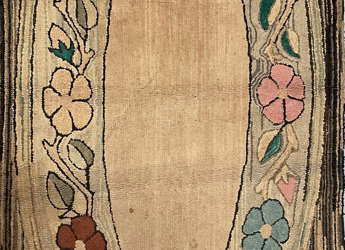 Floral oval detail showing coral, brown and dusty blue blossoms beside small spots in the peach-beige field.
