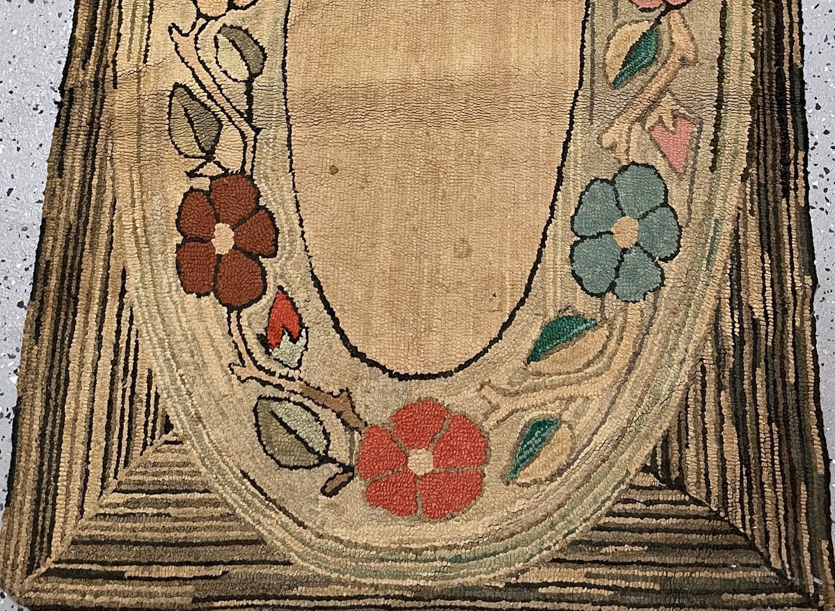 Full-length floral cotton rug showing the open oval centre and worn striped outer border.