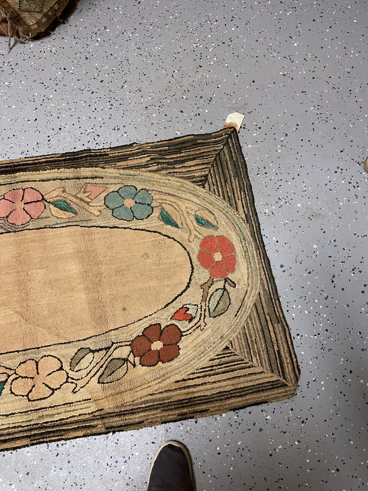 Angled corner view showing curling floral stems and localised wear along the geometric frame.