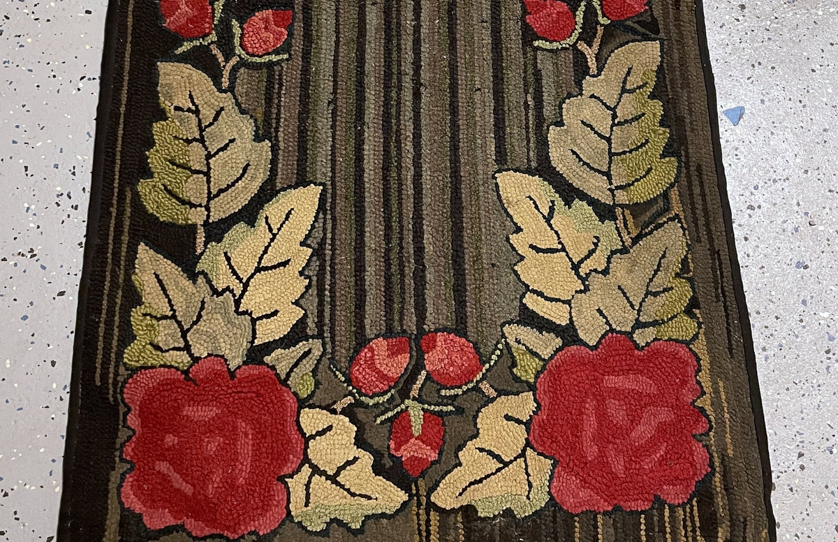Two red roses and small rosebuds framed by cream and olive leaves at the rug end.