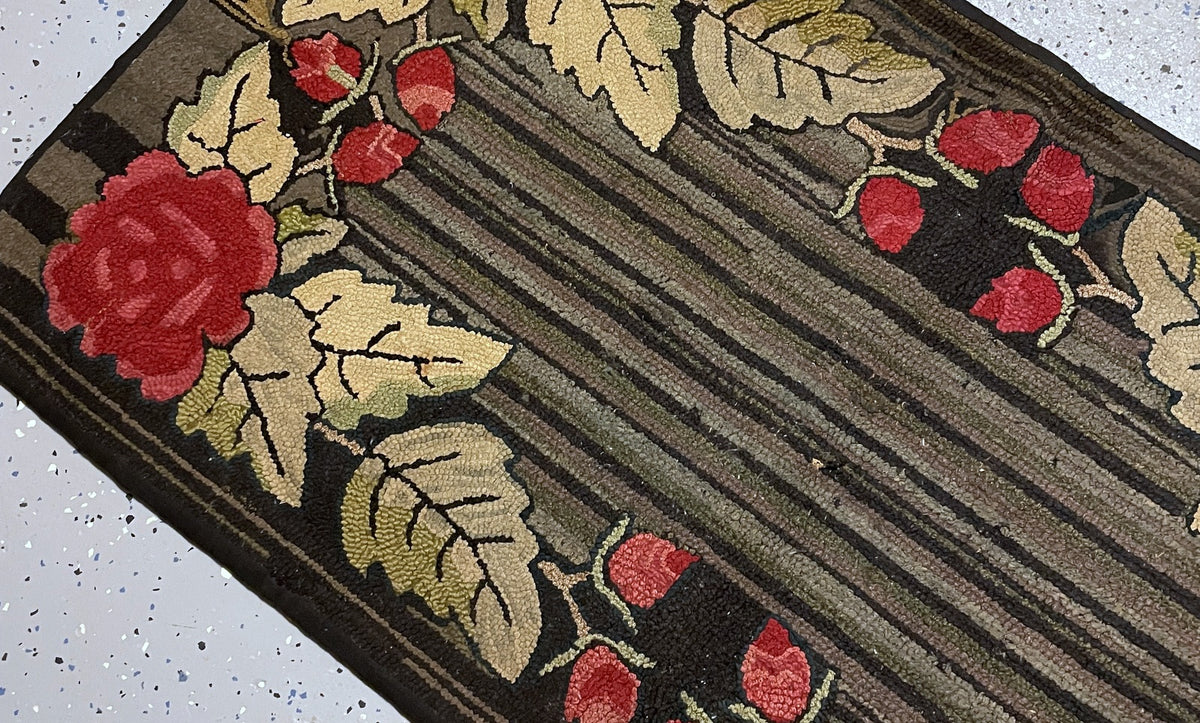 Close-up of taupe and charcoal hooked stripes with localised thinning beside red rosebuds and cream leaves.