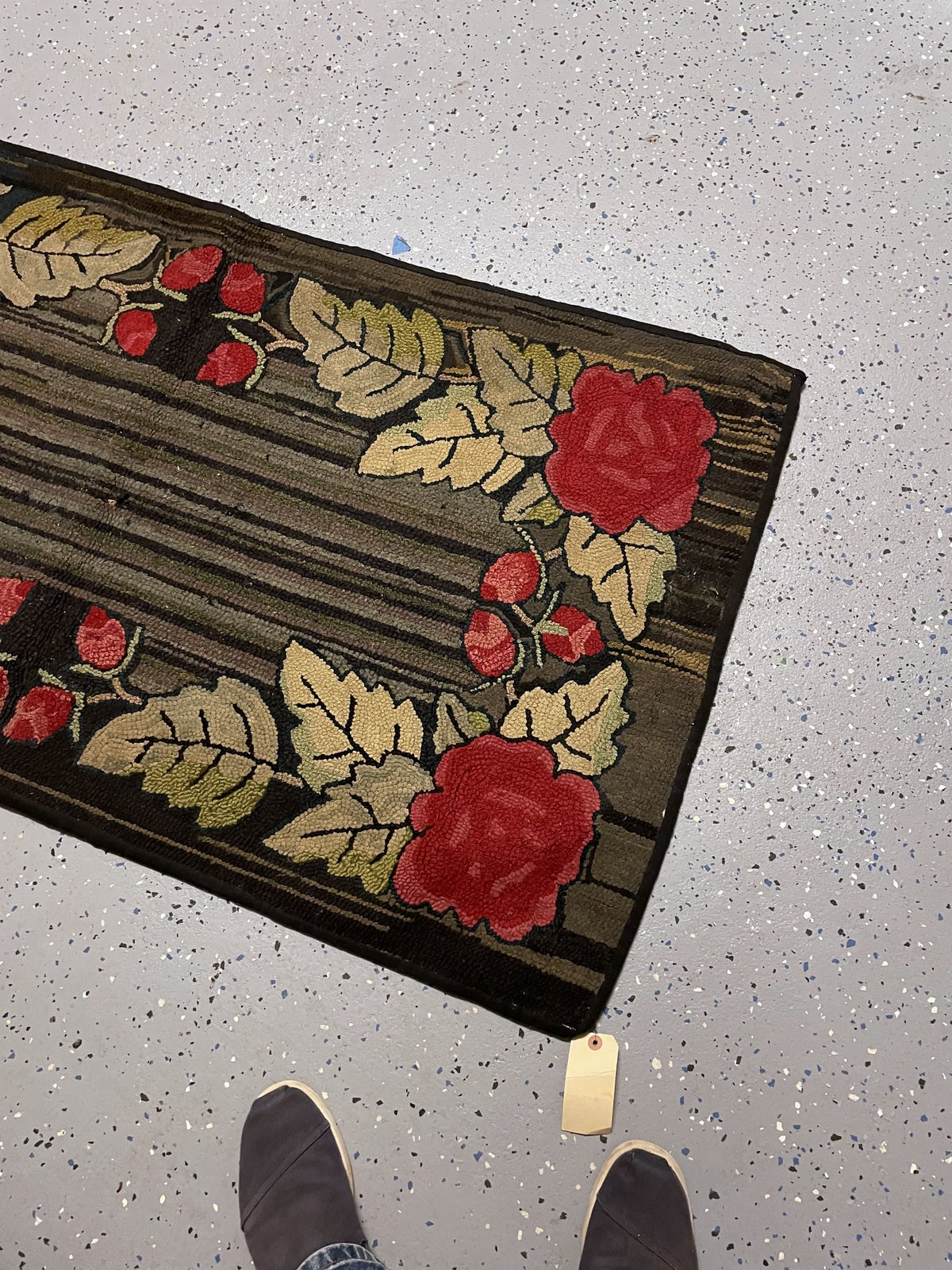 Rug end showing paired red roses, pale yellow foliage and dark bound edges.