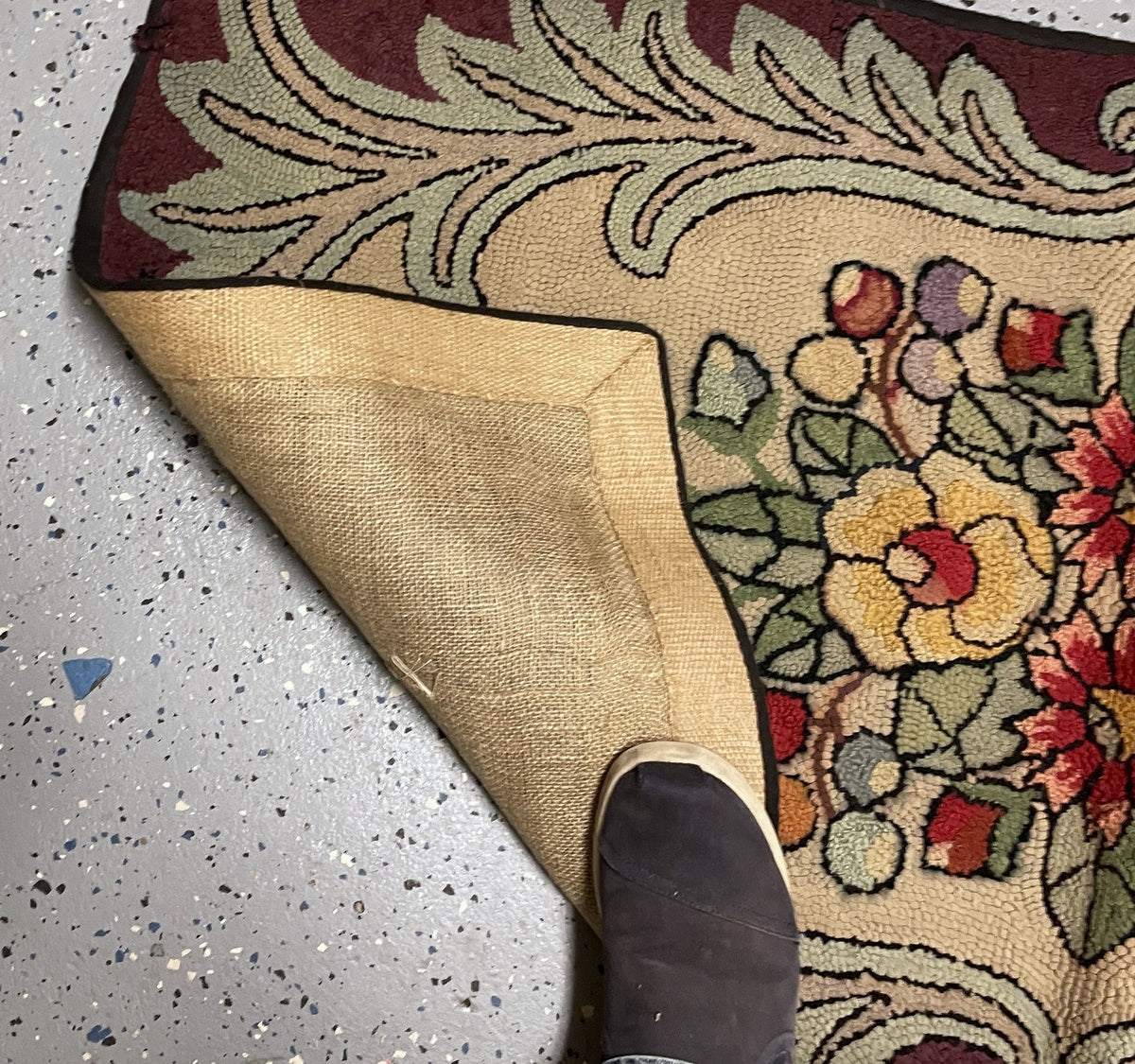Close-up of the tan woven reverse, dark bound edge and hooked yellow flowers beside sage foliage.