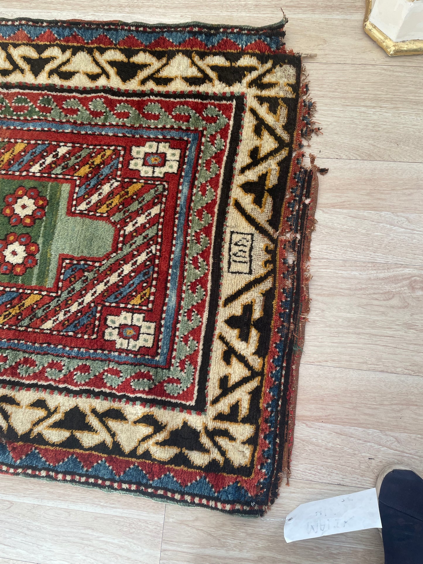 Full-pile antique Kazak rug with a visible damaged section on the original border, showcasing its authentic 1860s character.

