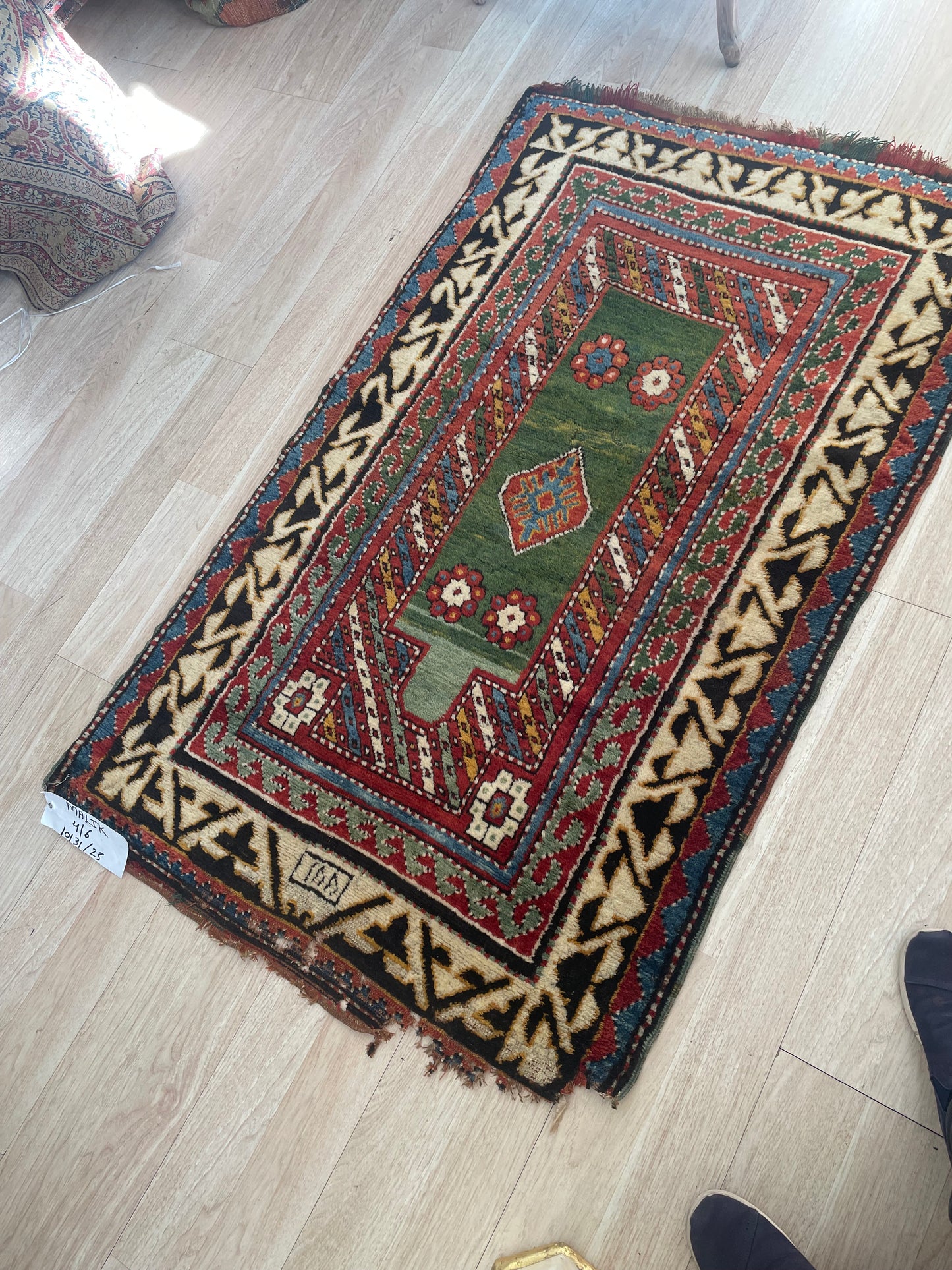 Stylized floral motifs and bold geometric patterns on the green field of an antique Caucasian Borchalu rug.

