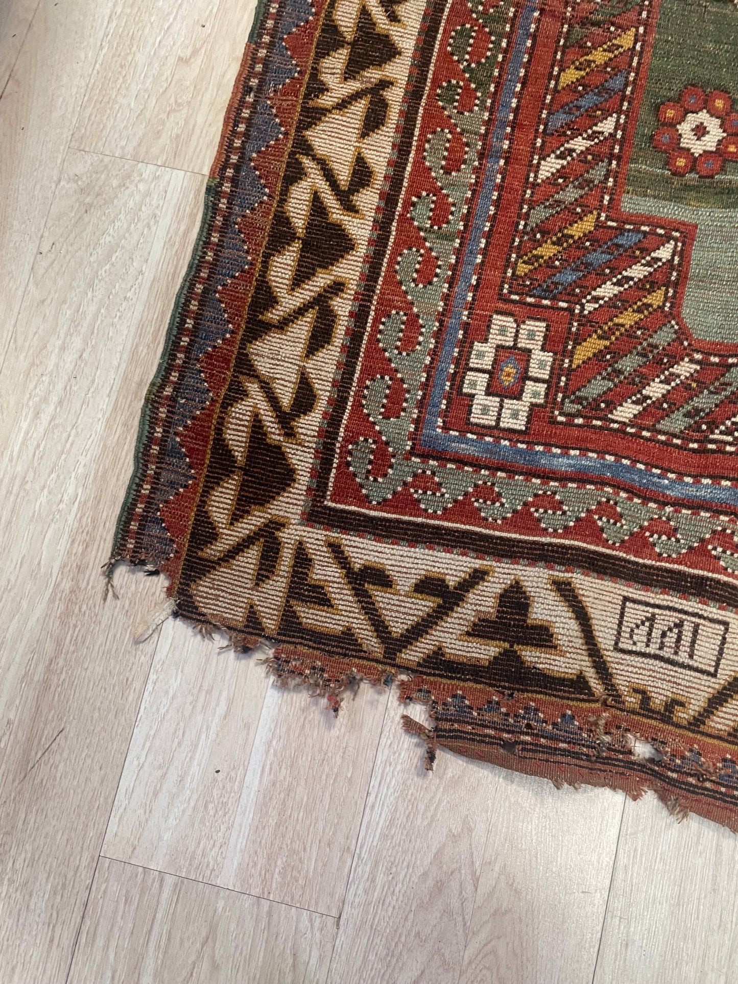A vintage-style Caucasian Borchalu Kazak rug with a green field, suitable for refined traditional or eclectic interiors.

