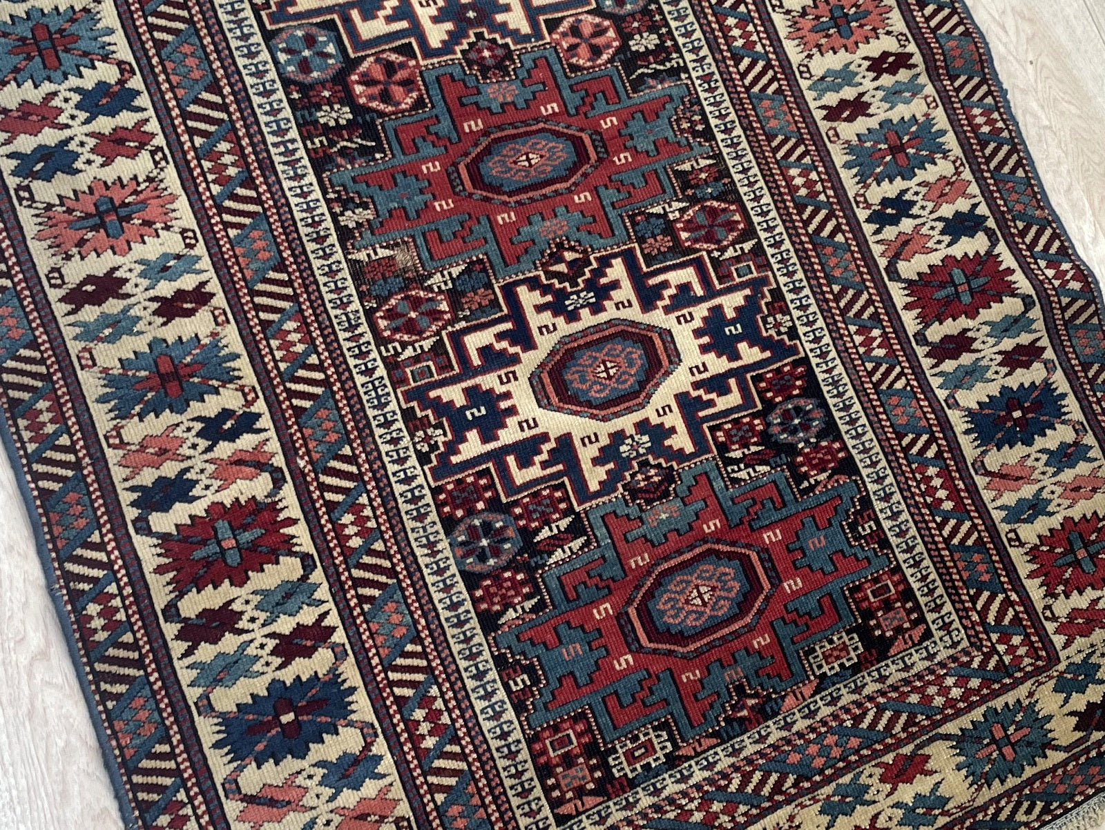 Close-up of antique Lezgi rug displaying sharp-edged geometric motifs and stylized Lezgi Stars

