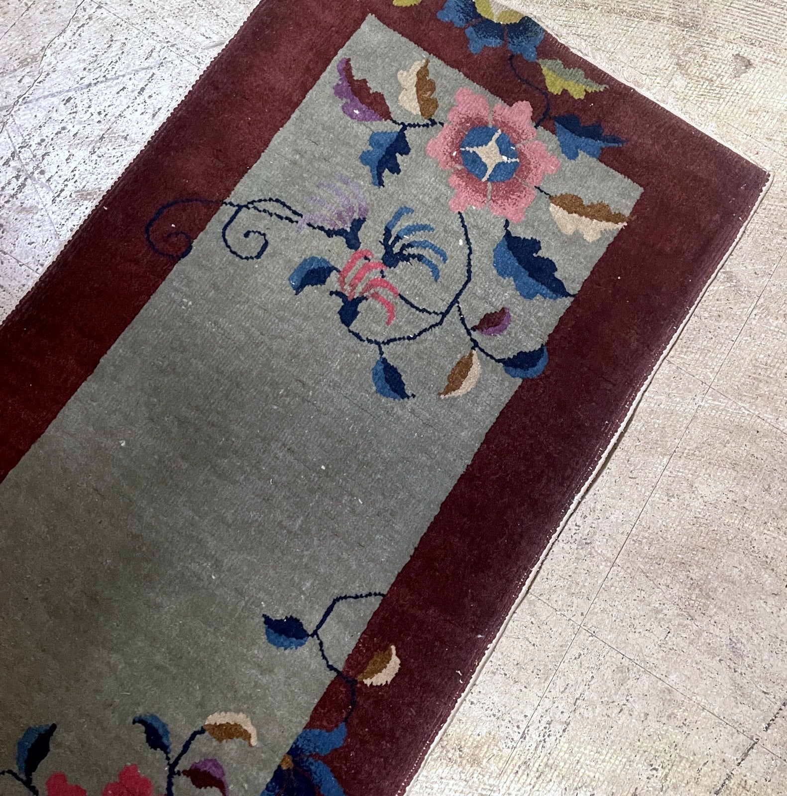 Close-up of antique Chinese Art Deco rug displaying asymmetrical floral spray design

