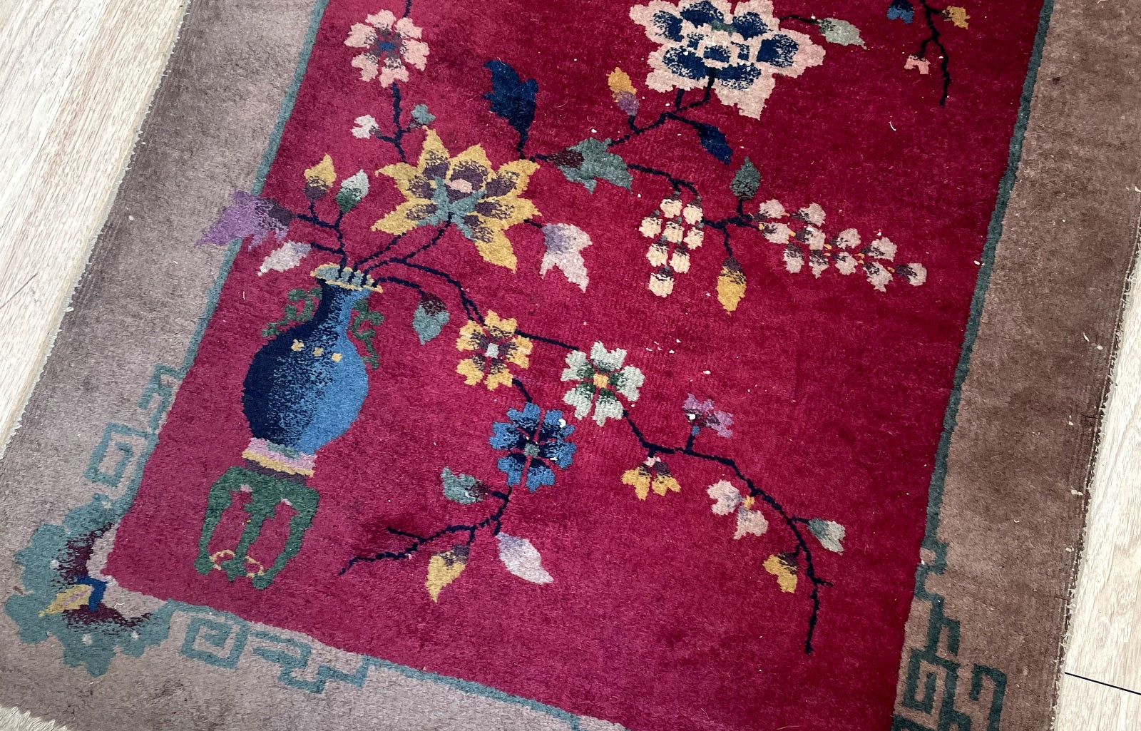 Close-up of antique Chinese Art Deco rug displaying traditional floral sprays and Greek key corner design

