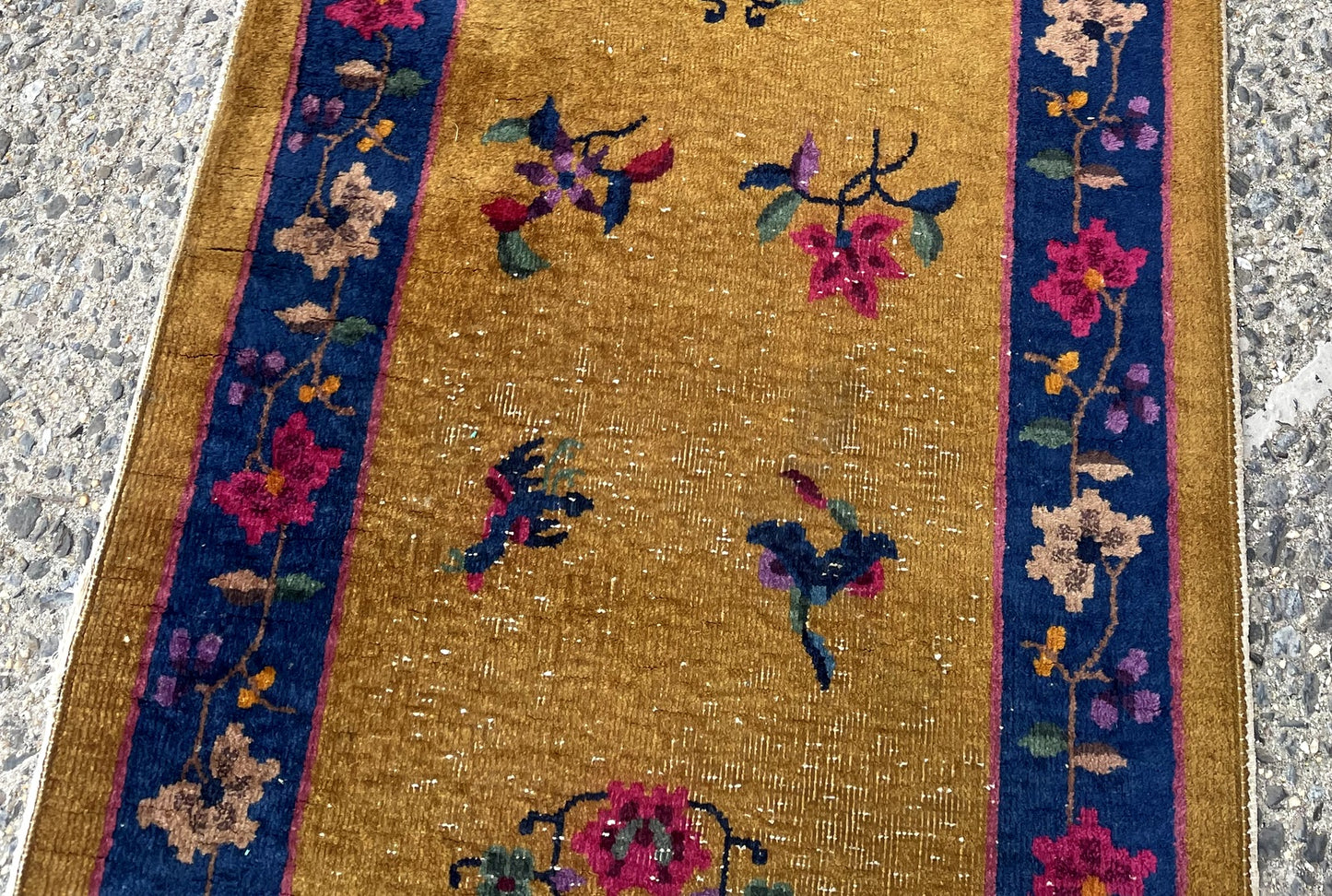 Close-up of antique Chinese Art Deco runner displaying sparse elegant floral sprays and butterfly motifs

