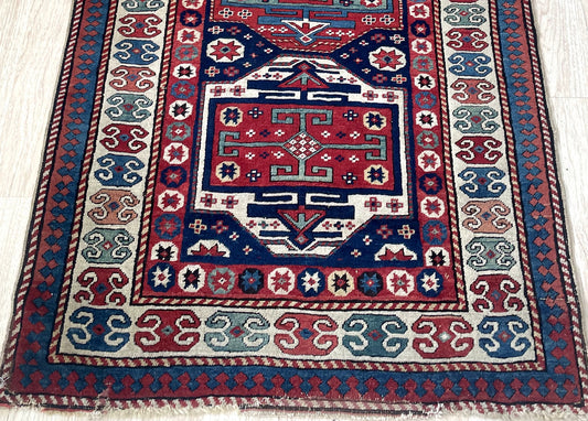 Late 19th century tribal rug from Caucasus Mountains with bold primitive design and madder red indigo colors on floor

