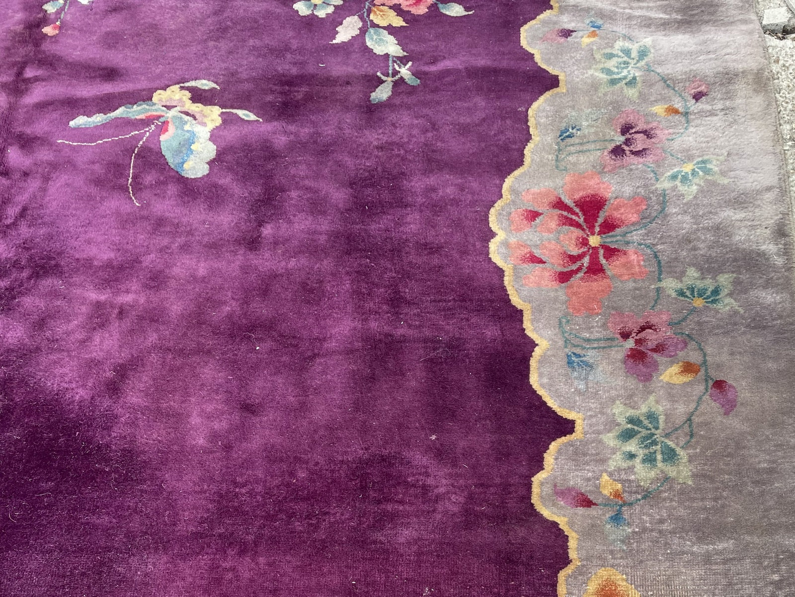 Room-size 1920s Chinese wool rug with an asymmetrical floral design, featuring steel blue chrysanthemums, trailing cherry blossoms, and a muted taupe outer border with floral sprays.

